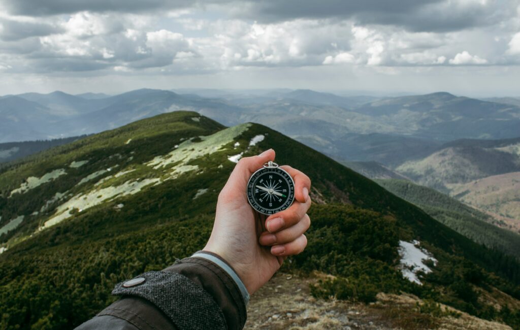 Kompass in der Hand mit Bergen im Hintergrund